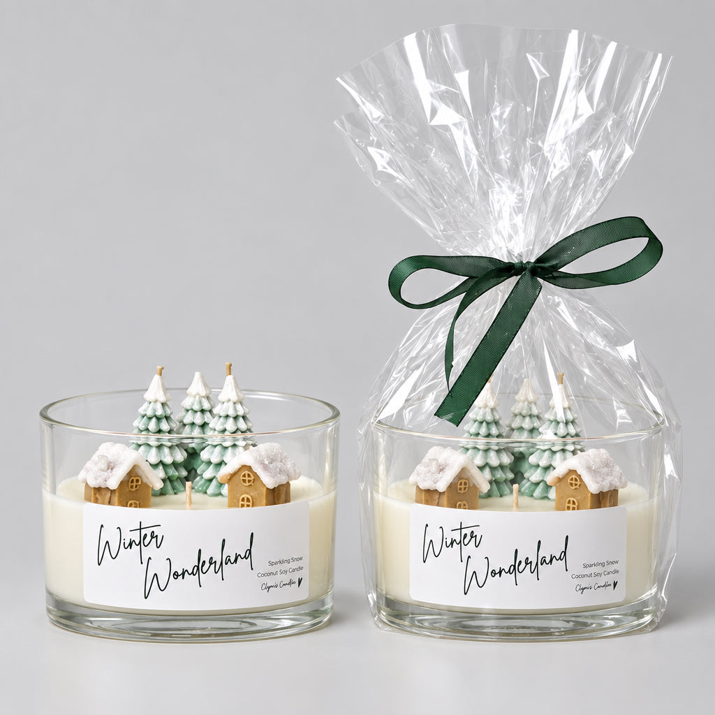 Two 'Winter Wonderland' scented candles displayed on a white shelf against a white wall. The left candle is in a clear glass jar with a white label and small decorative tree figures.